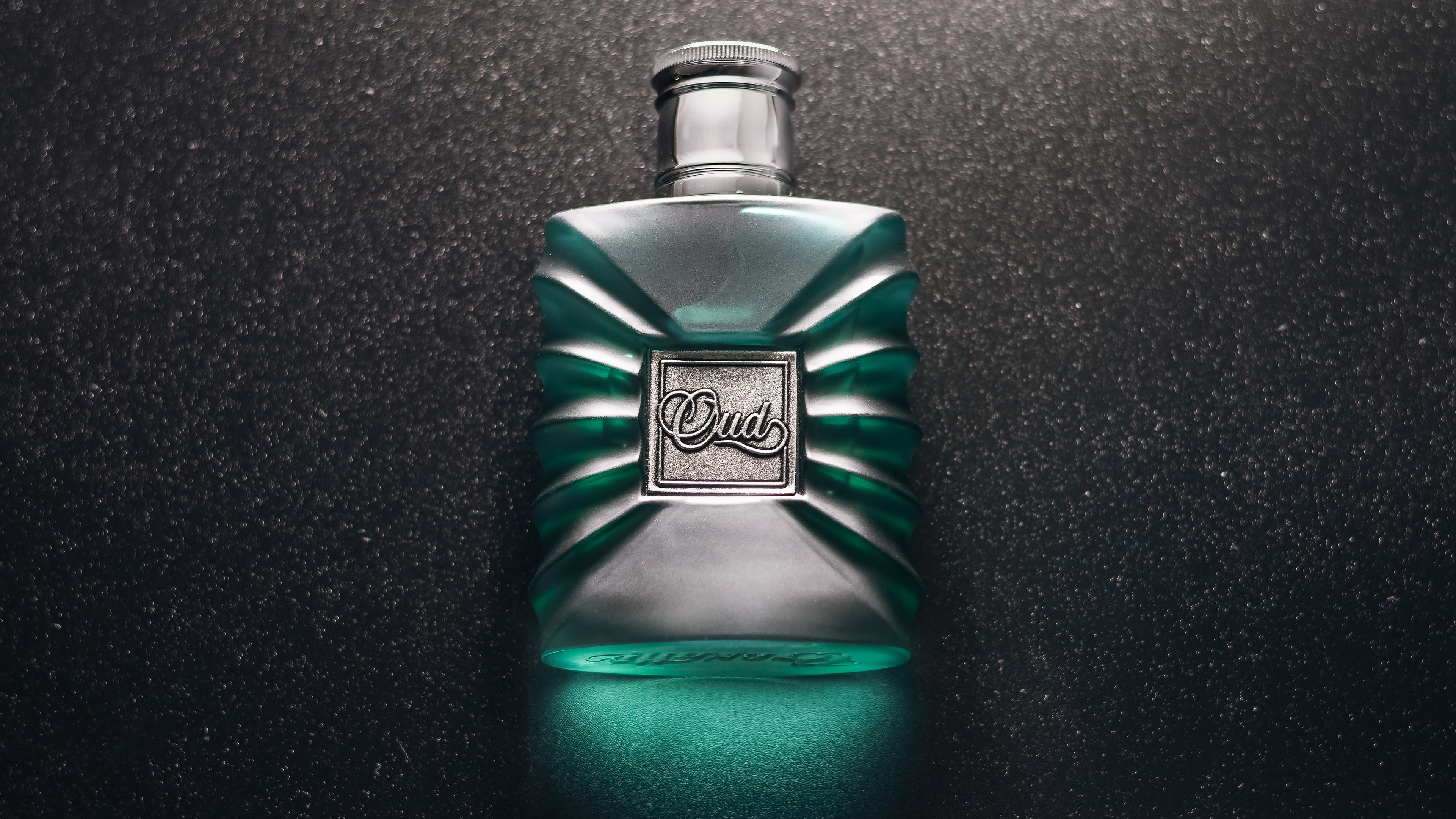 Botella de perfume Croxatto Oud, color verde-azul y fondo negro.